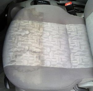A cloth car seat, half of it still soiled and half shampooed clean.